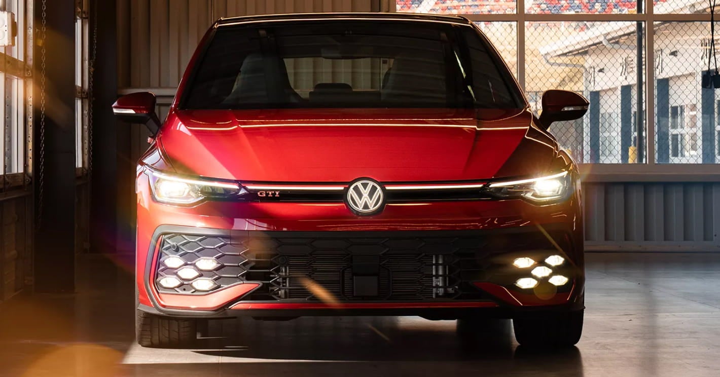 Front view of a red 2026 Volkswagen GTI parked in a dimly lit garage.