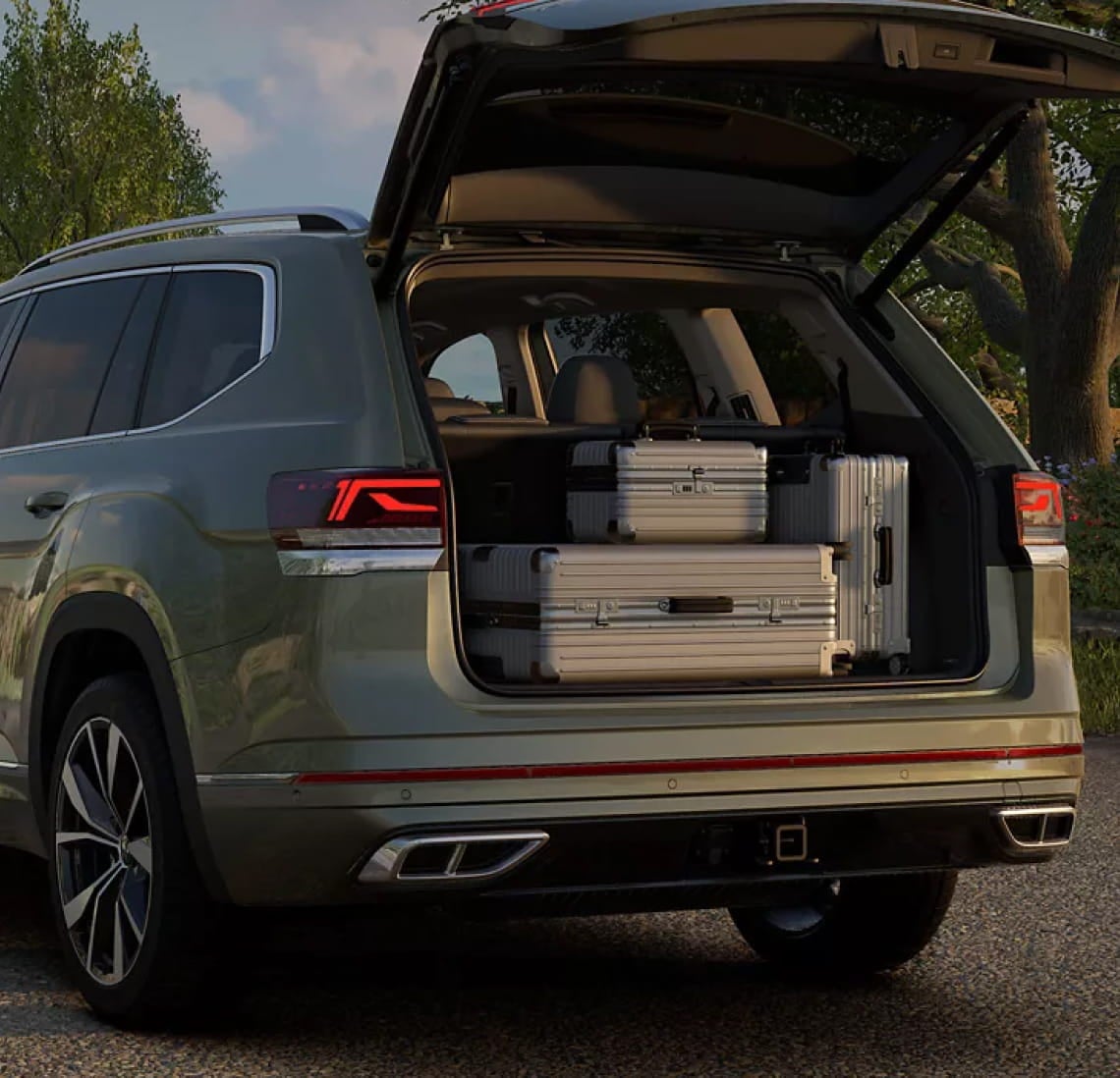 Volkswagen Atlas with its rear liftgate open, showing multiple suitcases stored in the cargo area.